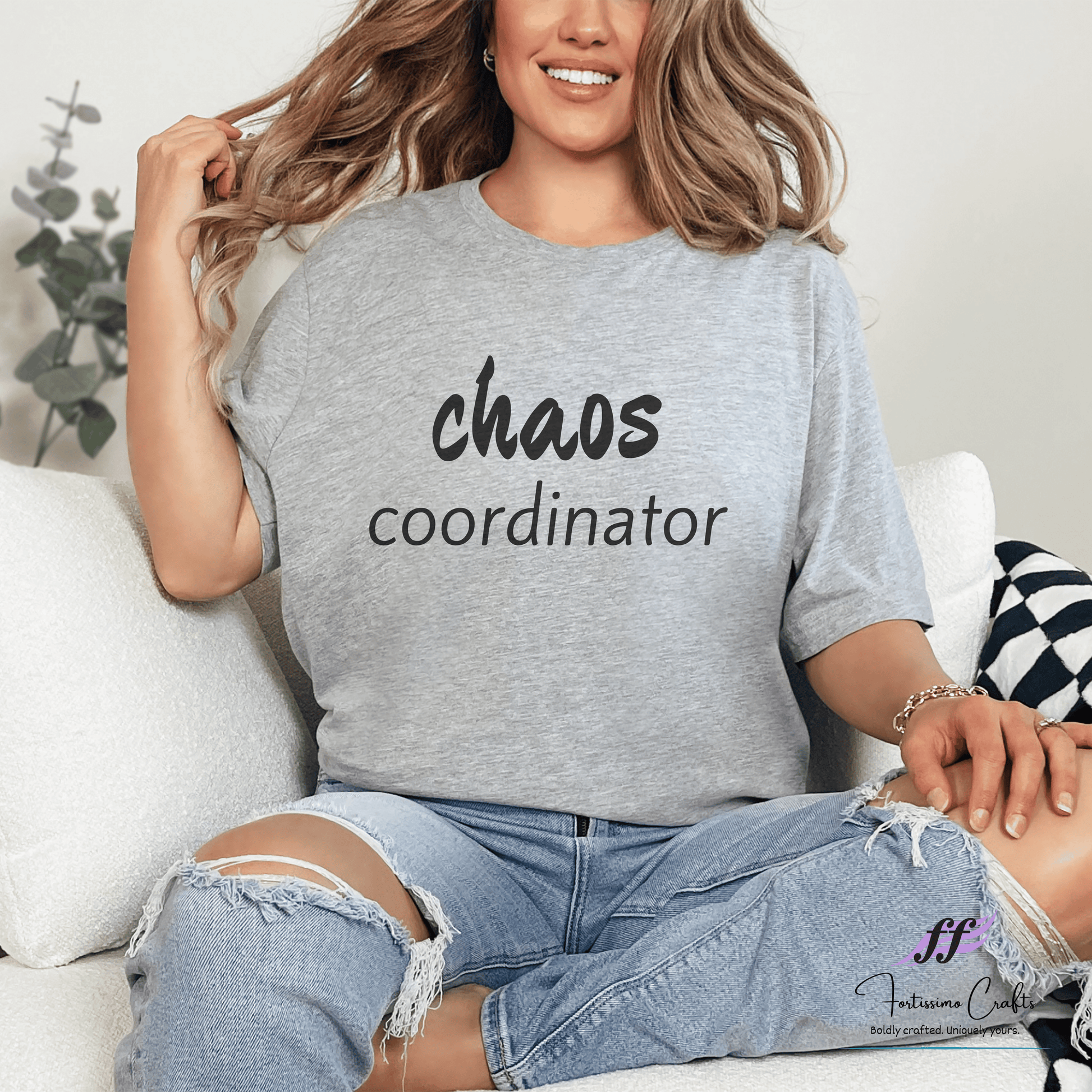 Person wearing a gray t-shirt with 'chaos coordinator' text, sitting on a couch.