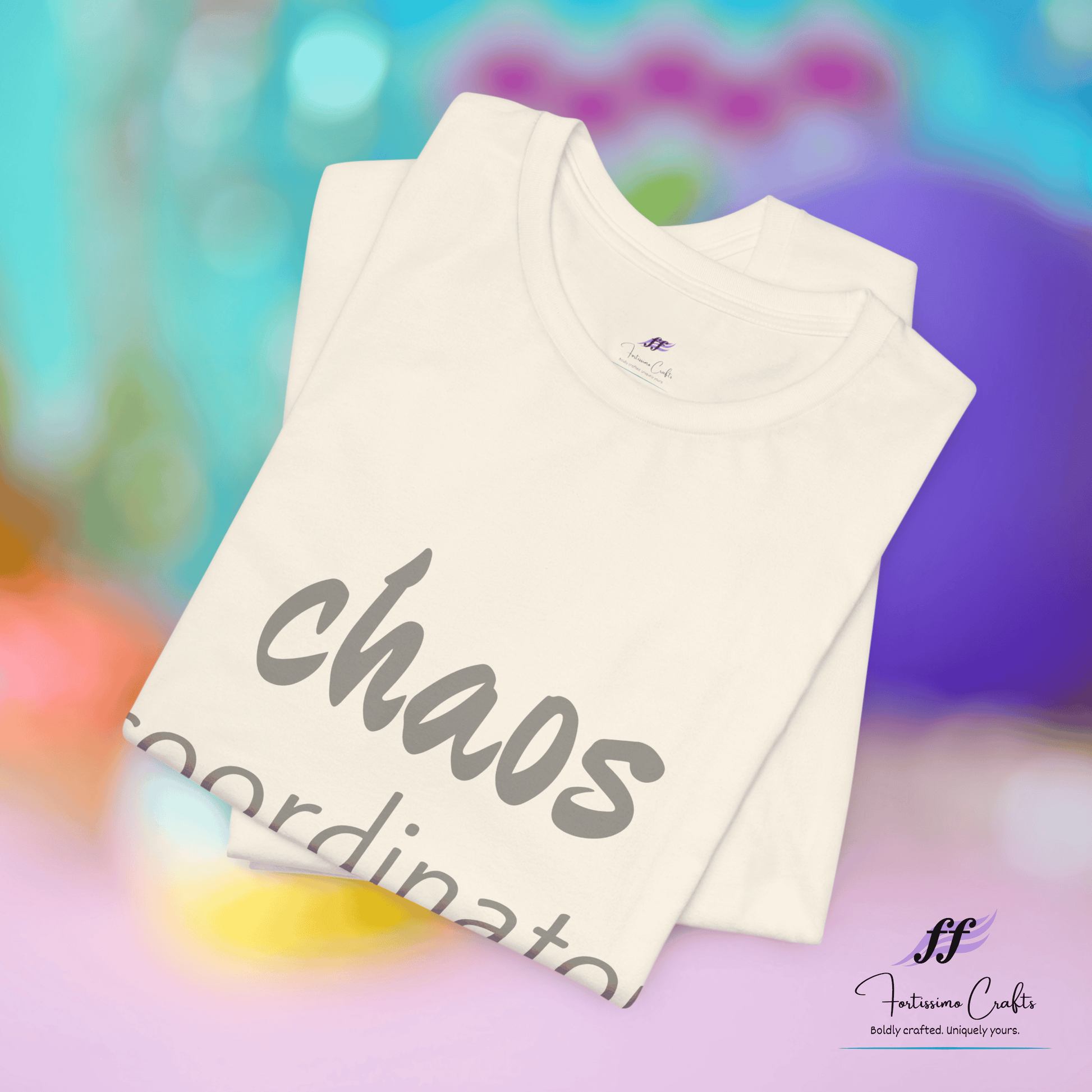 Folded white t-shirt with 'chaos' text on a colorful blurred background