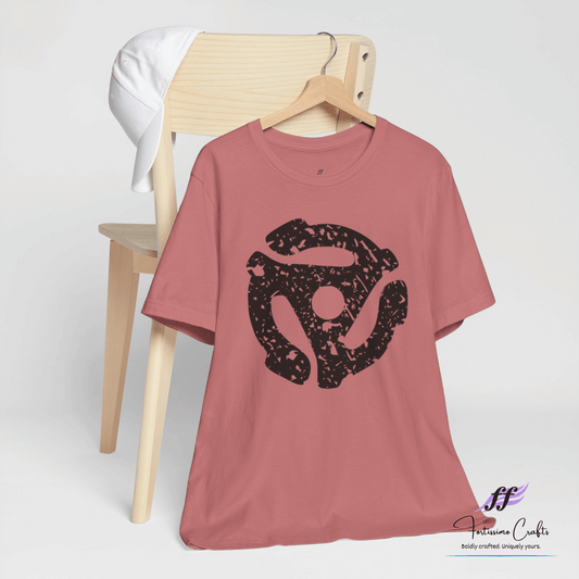 Pink t-shirt with a black graphic design on a wooden chair against a white background