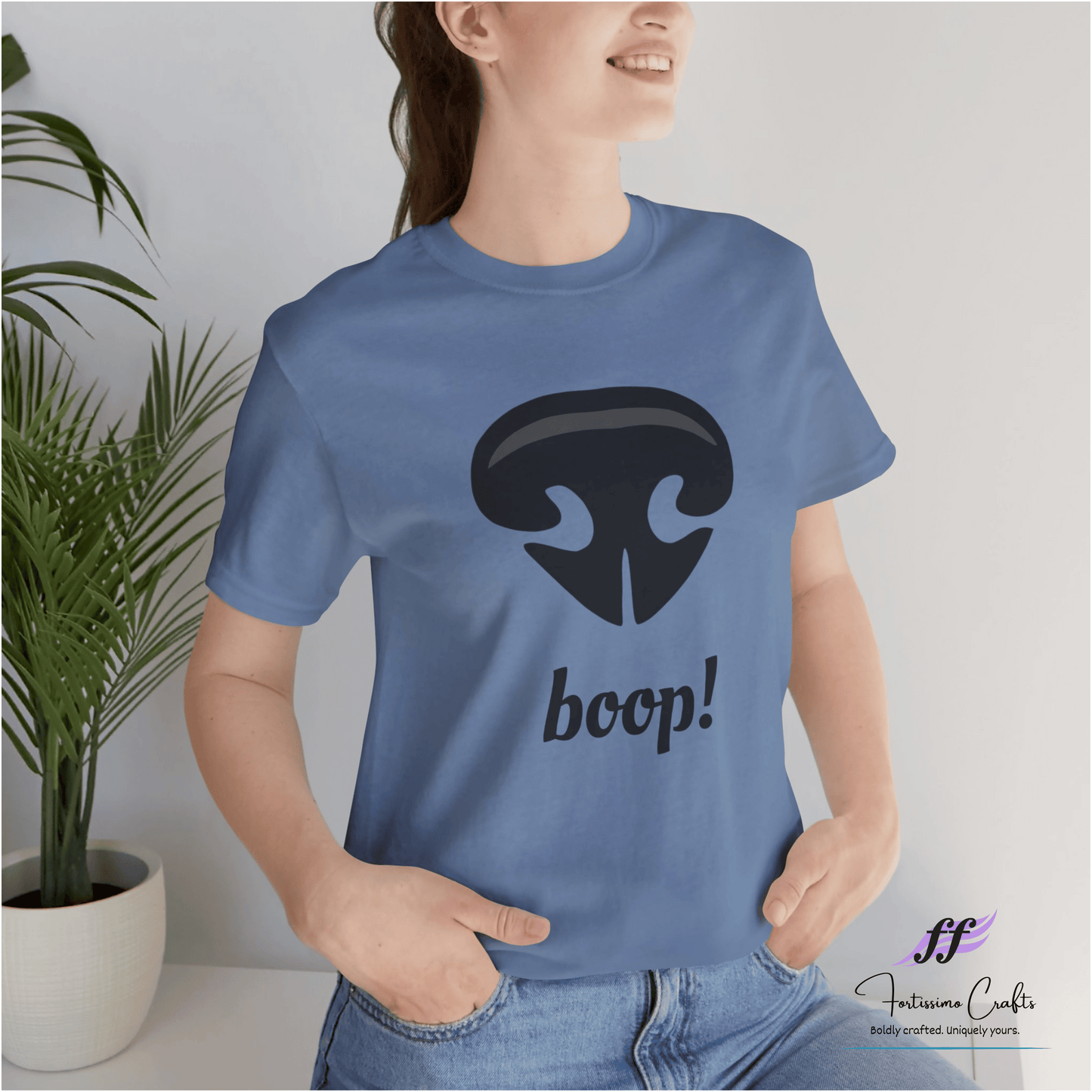 Person wearing a blue t-shirt with a black dog nose and 'boop!' text, standing indoors.