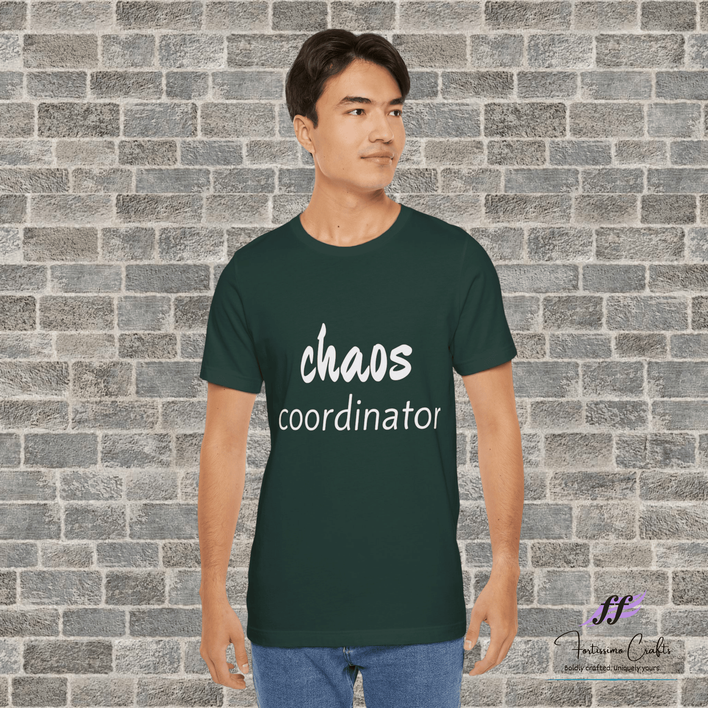 Person wearing a green t-shirt with 'chaos coordinator' text against a brick wall.