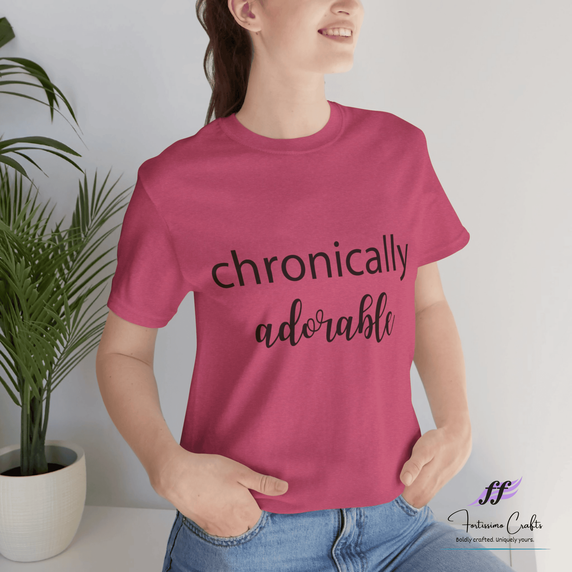 Person wearing a pink t-shirt with 'chronically adorable' text, standing against a plain background.