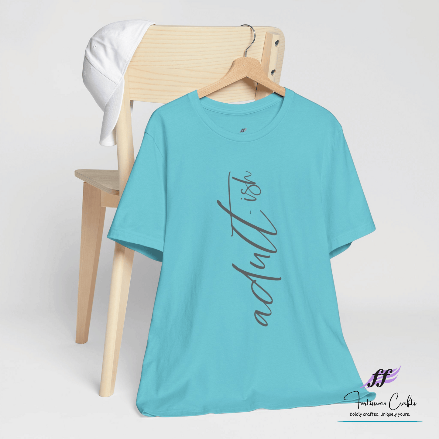 Turquoise t-shirt with 'adultish' text on a wooden chair against a white background