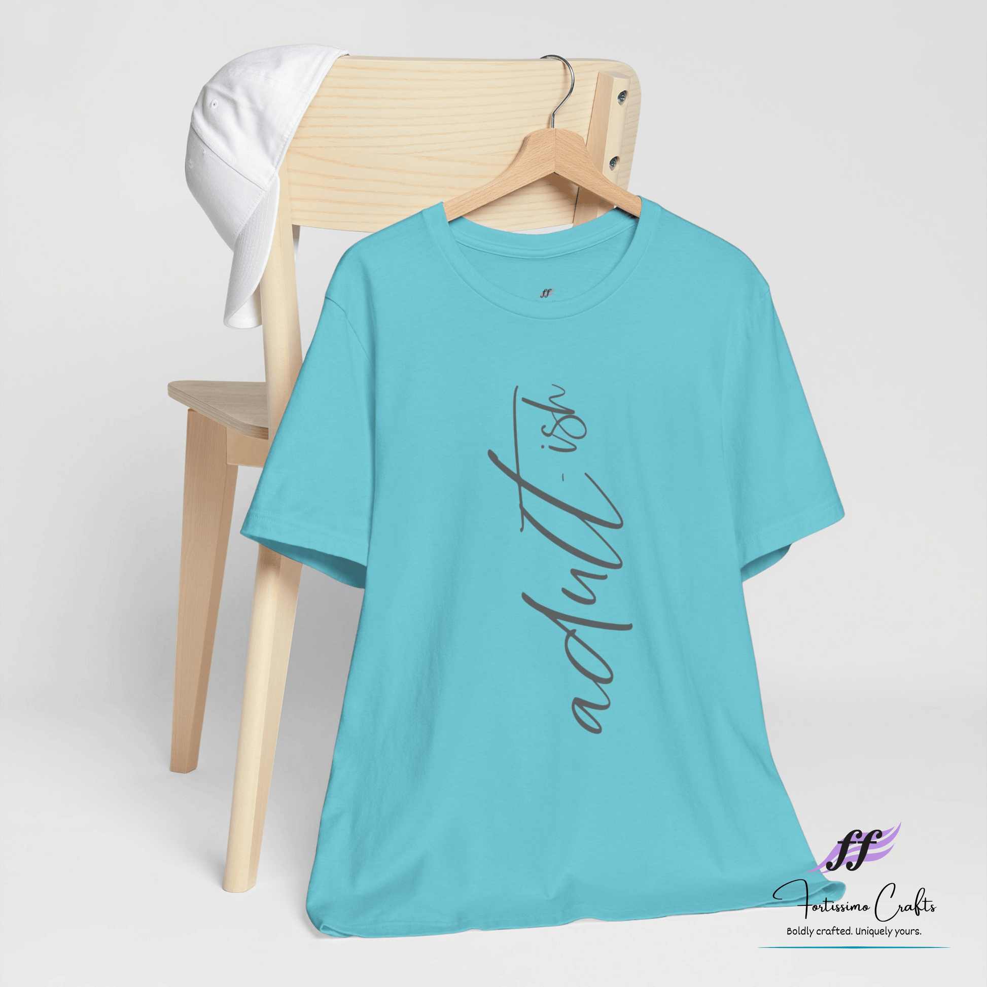Turquoise t-shirt with 'adultish' text on a wooden chair against a white background