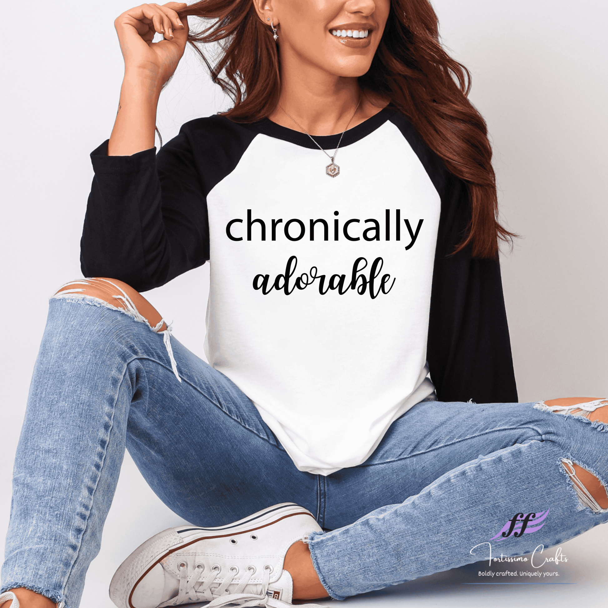 Woman wearing a black and white 'chronically adorable' shirt with ripped jeans.