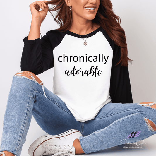 Woman wearing a black and white 'chronically adorable' shirt with ripped jeans.