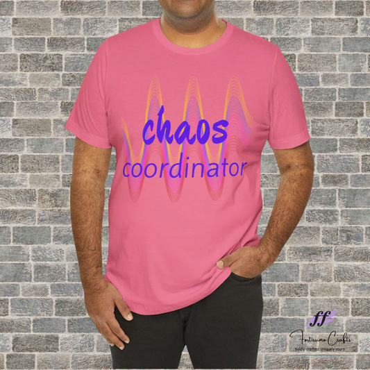 Person wearing a pink t-shirt with 'chaos coordinator' text against a brick wall.