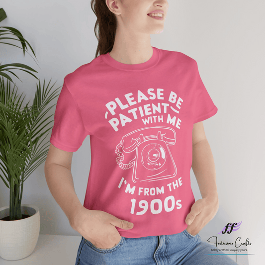 Person wearing a pink t-shirt with a vintage phone graphic and text, standing against a plain background.