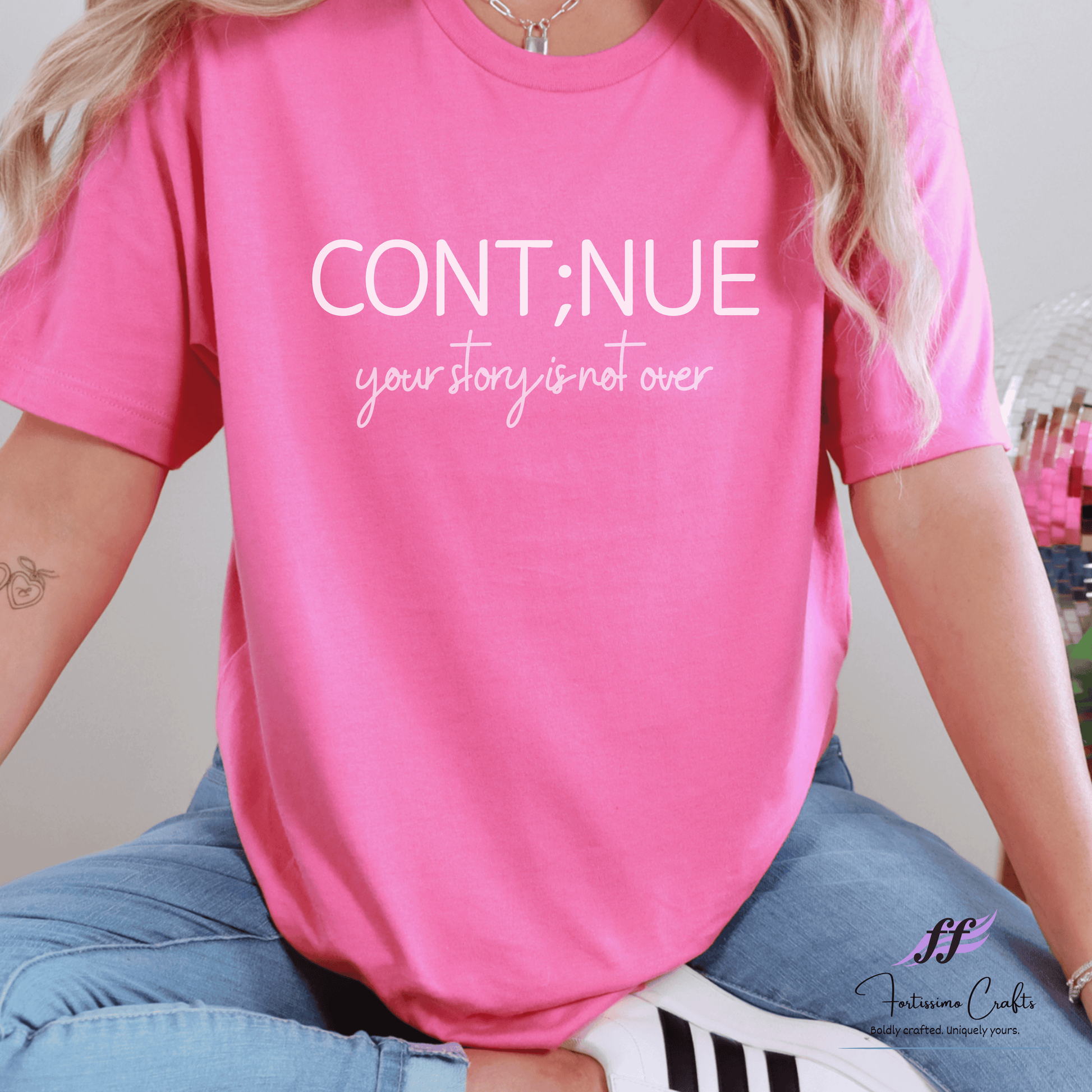 Person wearing a pink t-shirt with motivational text and denim jeans.