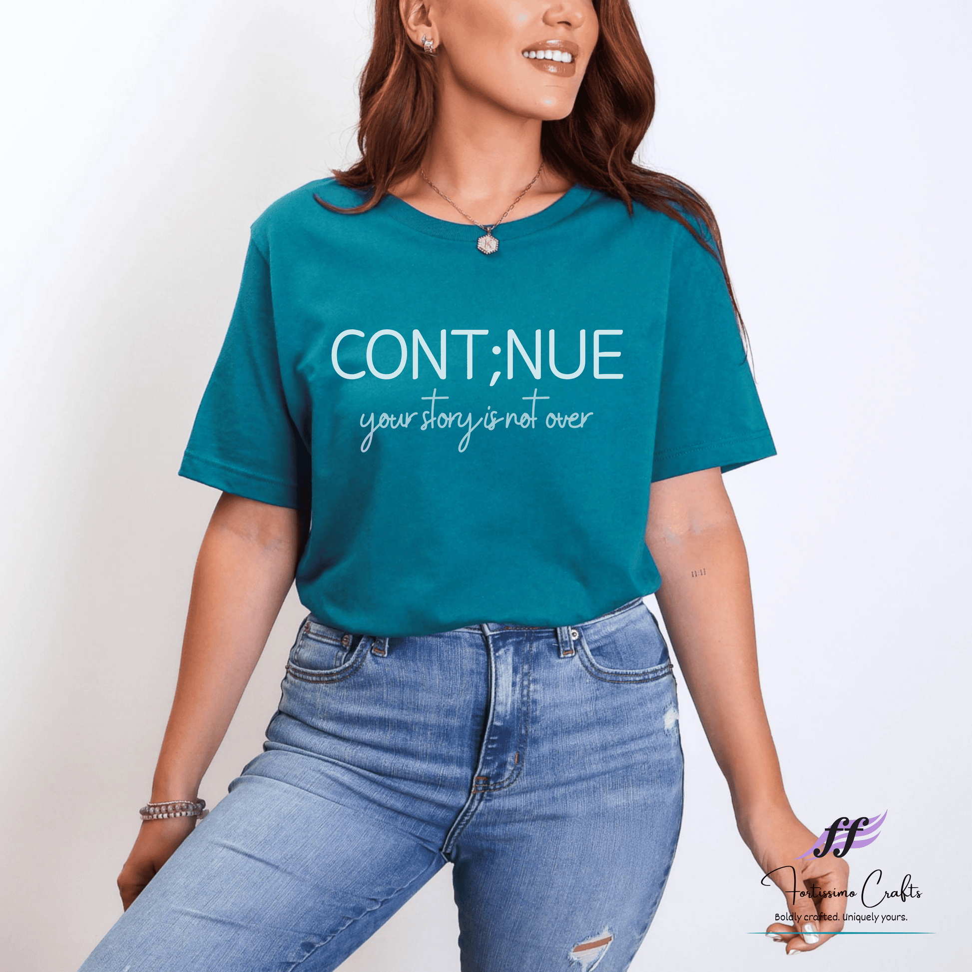 Woman wearing a teal t-shirt with motivational text on a plain background