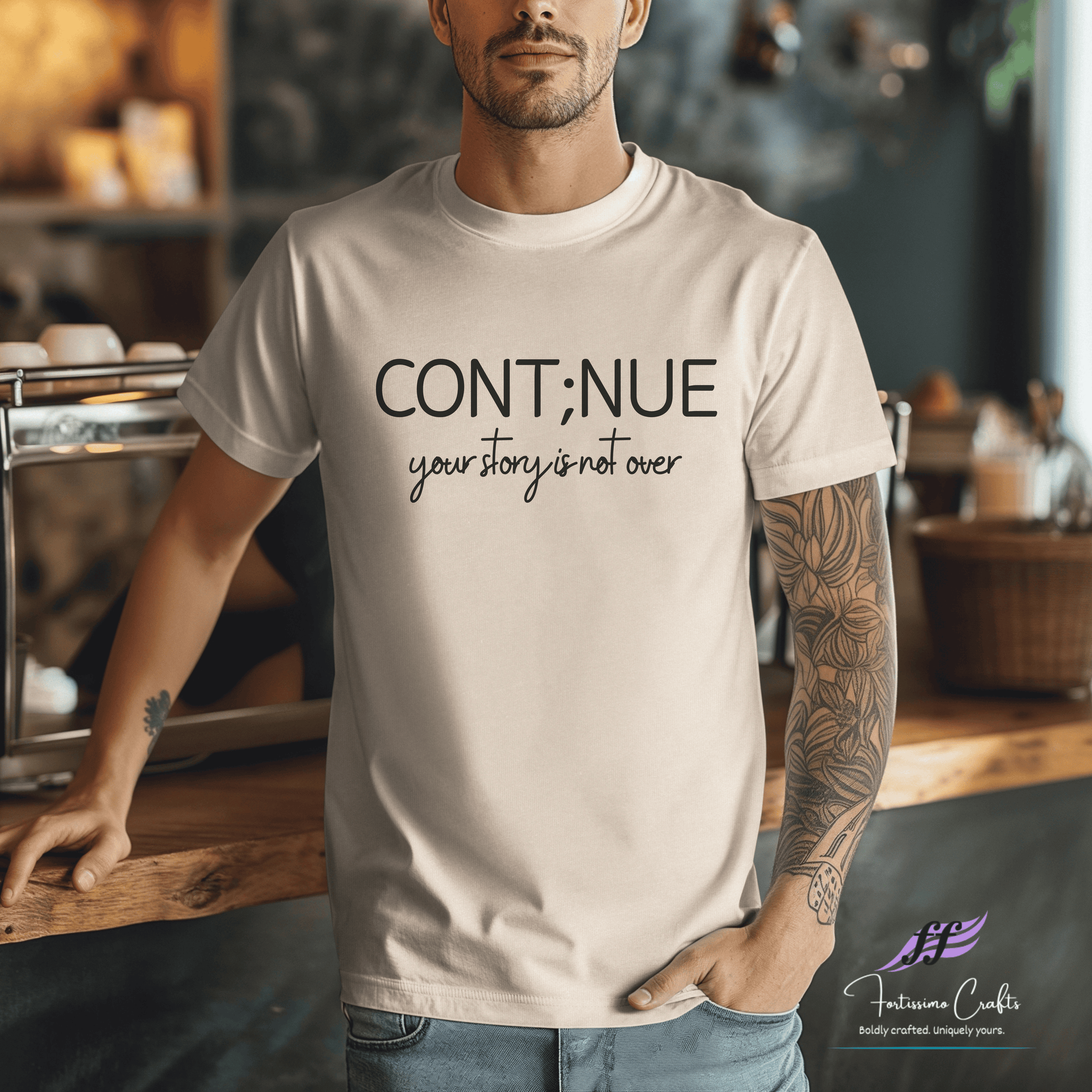 Man wearing a beige t-shirt with motivational text in a coffee shop setting