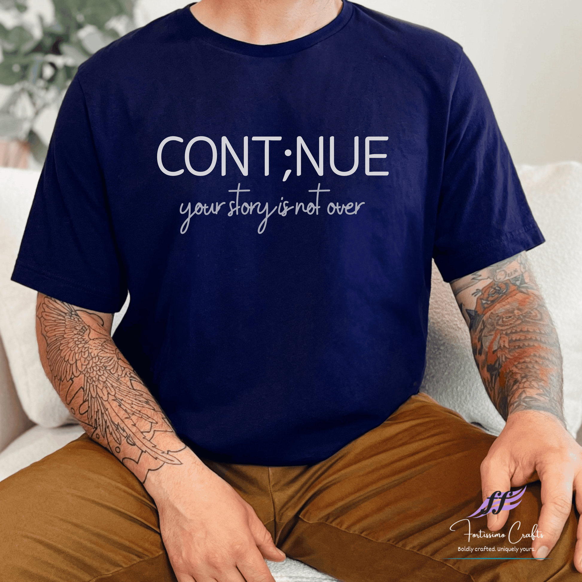 Person wearing a navy blue t-shirt with 'CONT;NUE your story is not over' text.