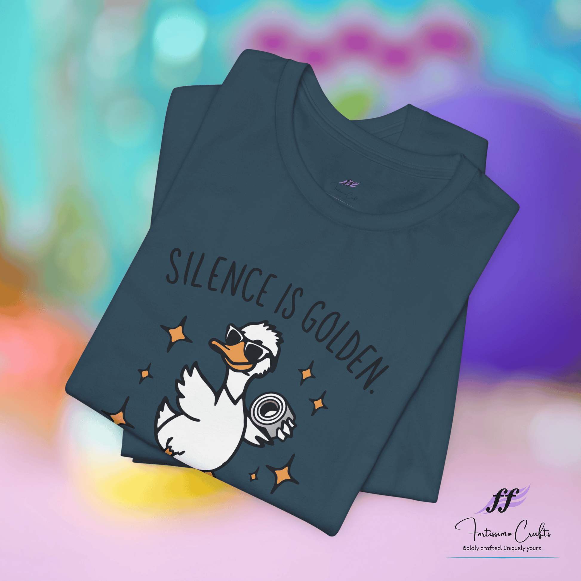 Folded t-shirt with a duck graphic and 'Silence is Golden' text on a colorful background