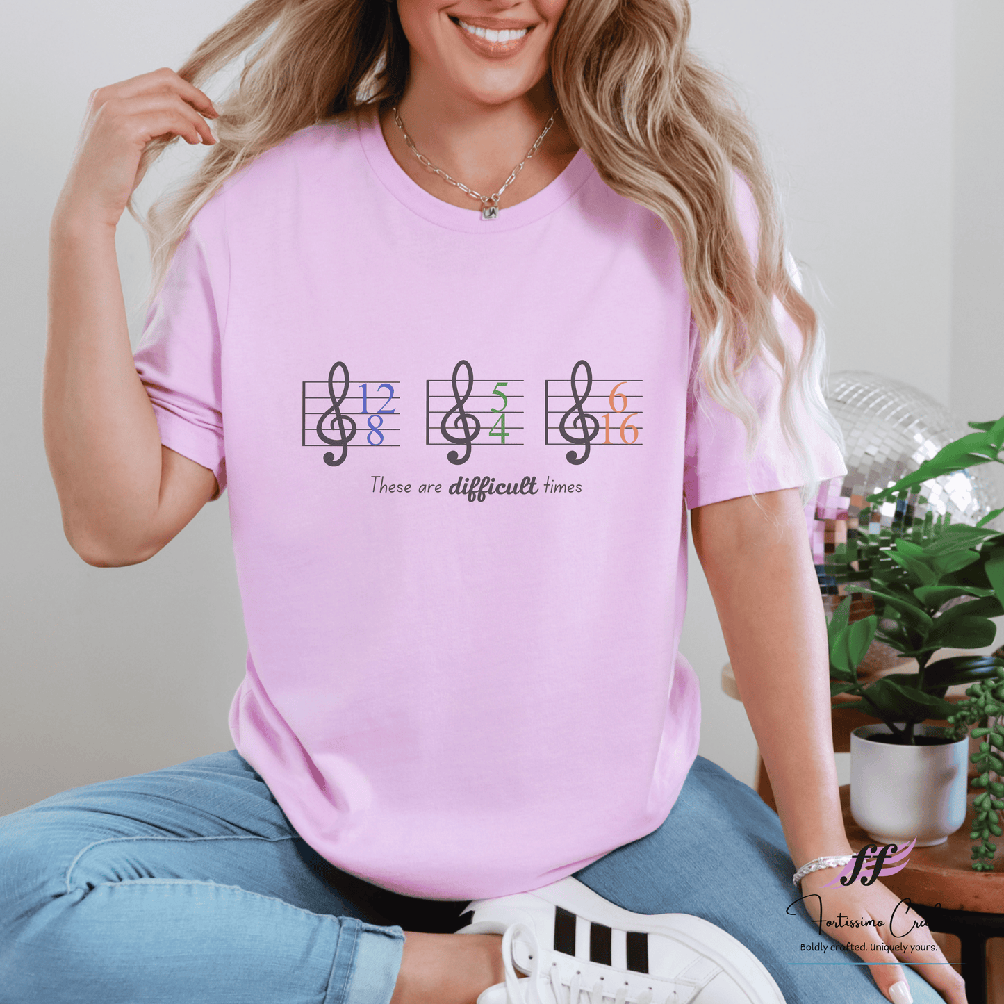 Woman wearing a pink t-shirt with musical notes and text, sitting indoors.