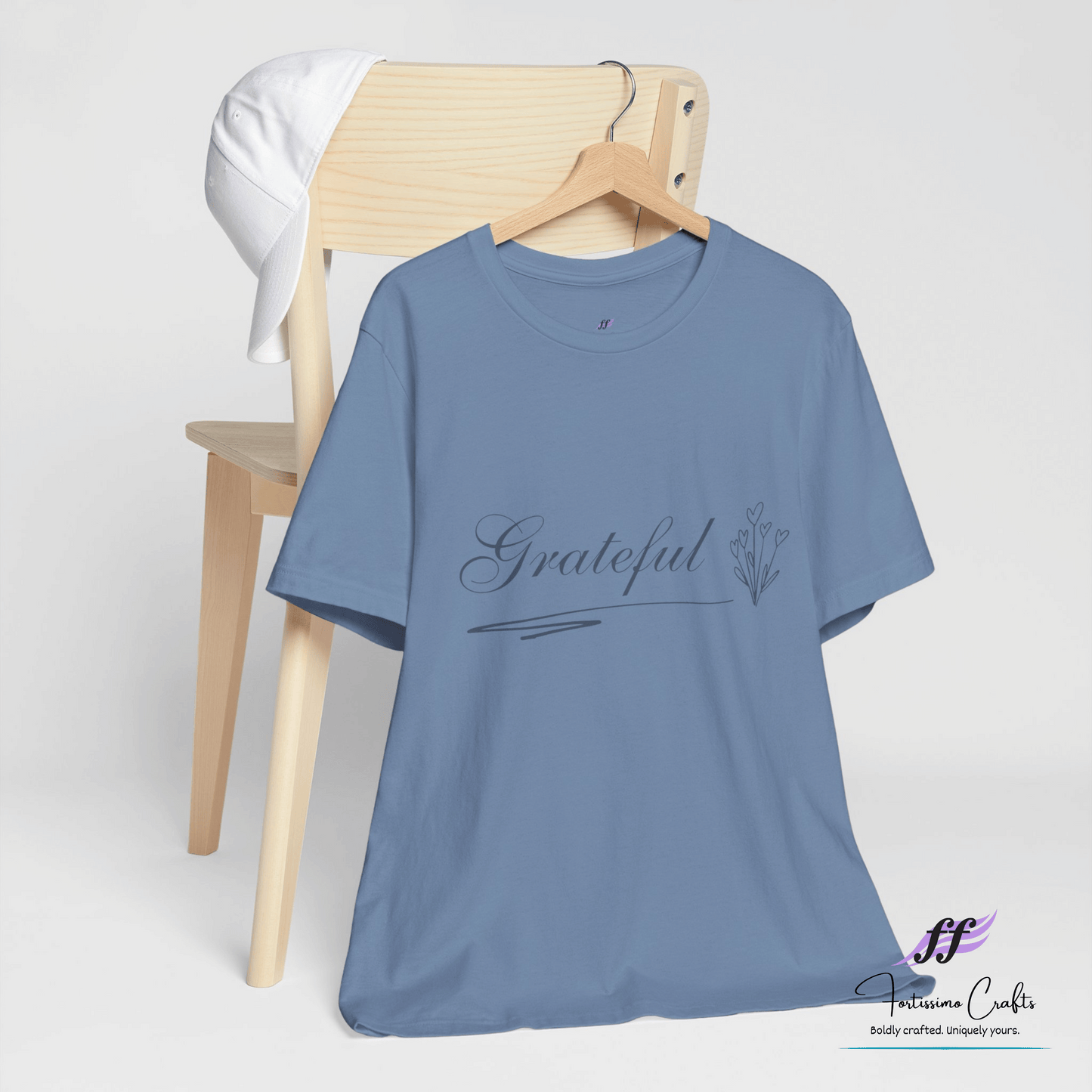 Blue t-shirt with 'Grateful' text on a wooden chair against a white background