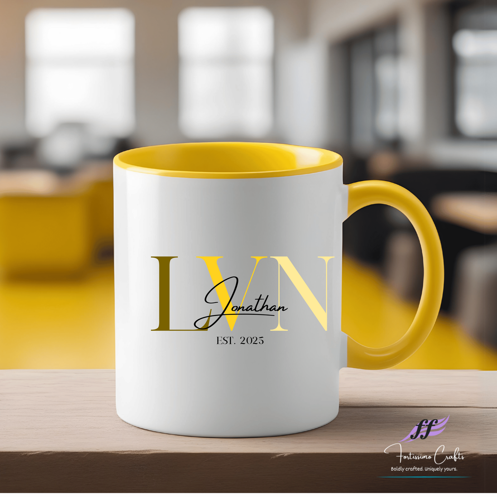 White mug with yellow interior and handle, featuring 'LVN Jonathan EST. 2023' text, on a blurred indoor background.
