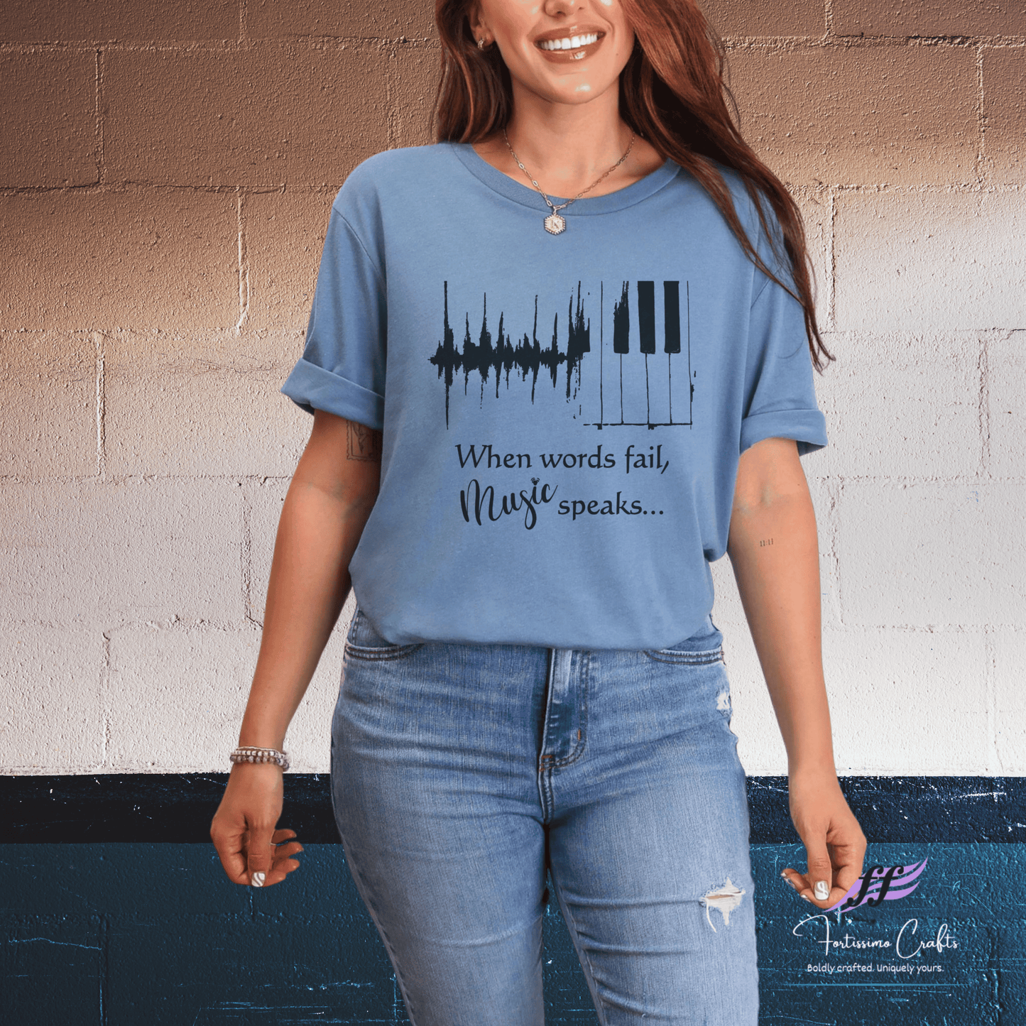 Woman wearing a blue t-shirt with musical design and text against a brick wall.