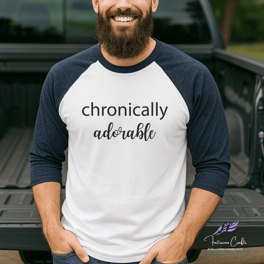 Man wearing a white and navy baseball shirt with 'chronically adorable' text, standing in front of a truck.