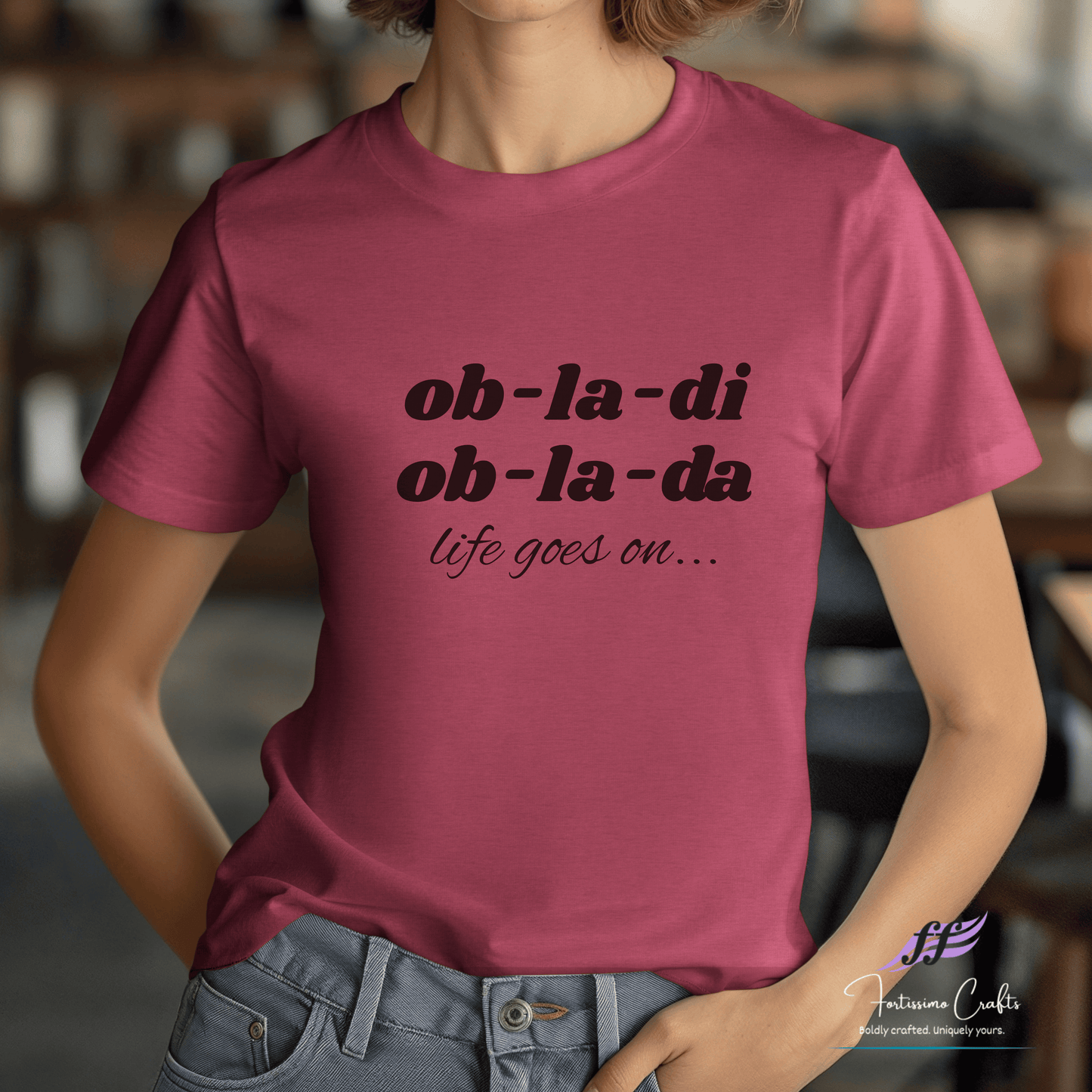 Person wearing a pink t-shirt with 'ob-la-di ob-la-da life goes on' text.