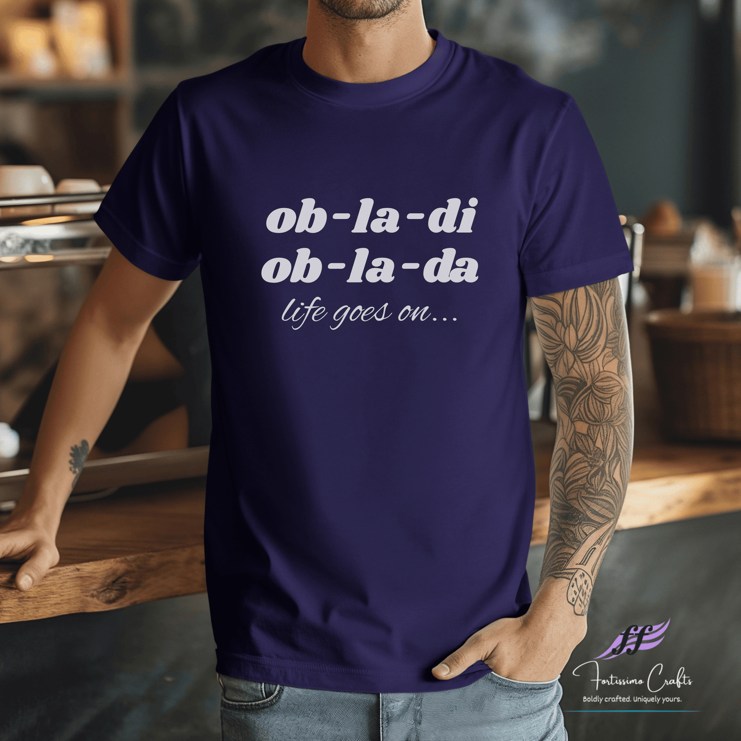 Person wearing a purple t-shirt with 'ob-la-di ob-la-da life goes on' text in a casual setting.