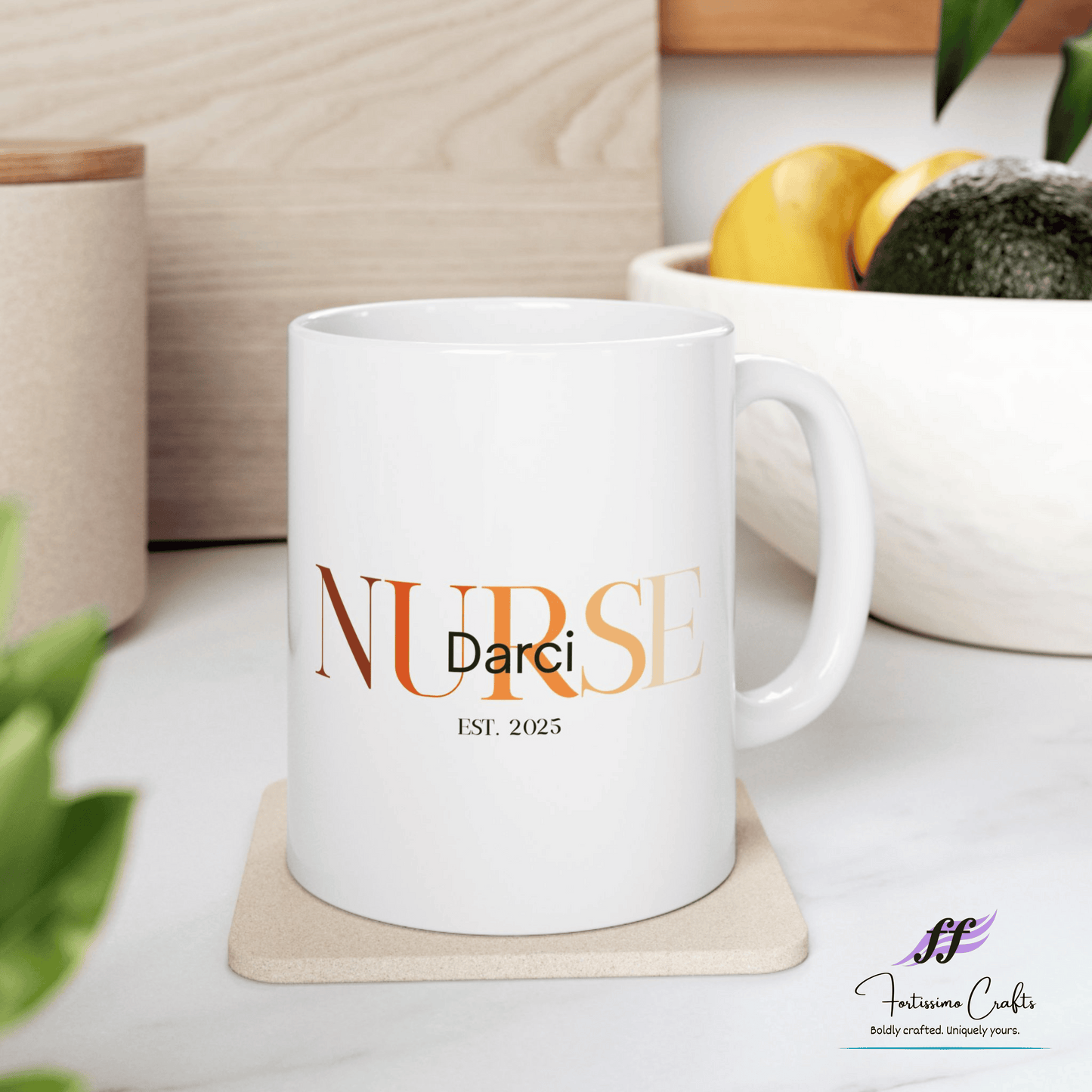White ceramic mugs with NURSE in orange with the name Darci on top and est. 2025 underneath sitting on a table with a bowl of fruit in the background