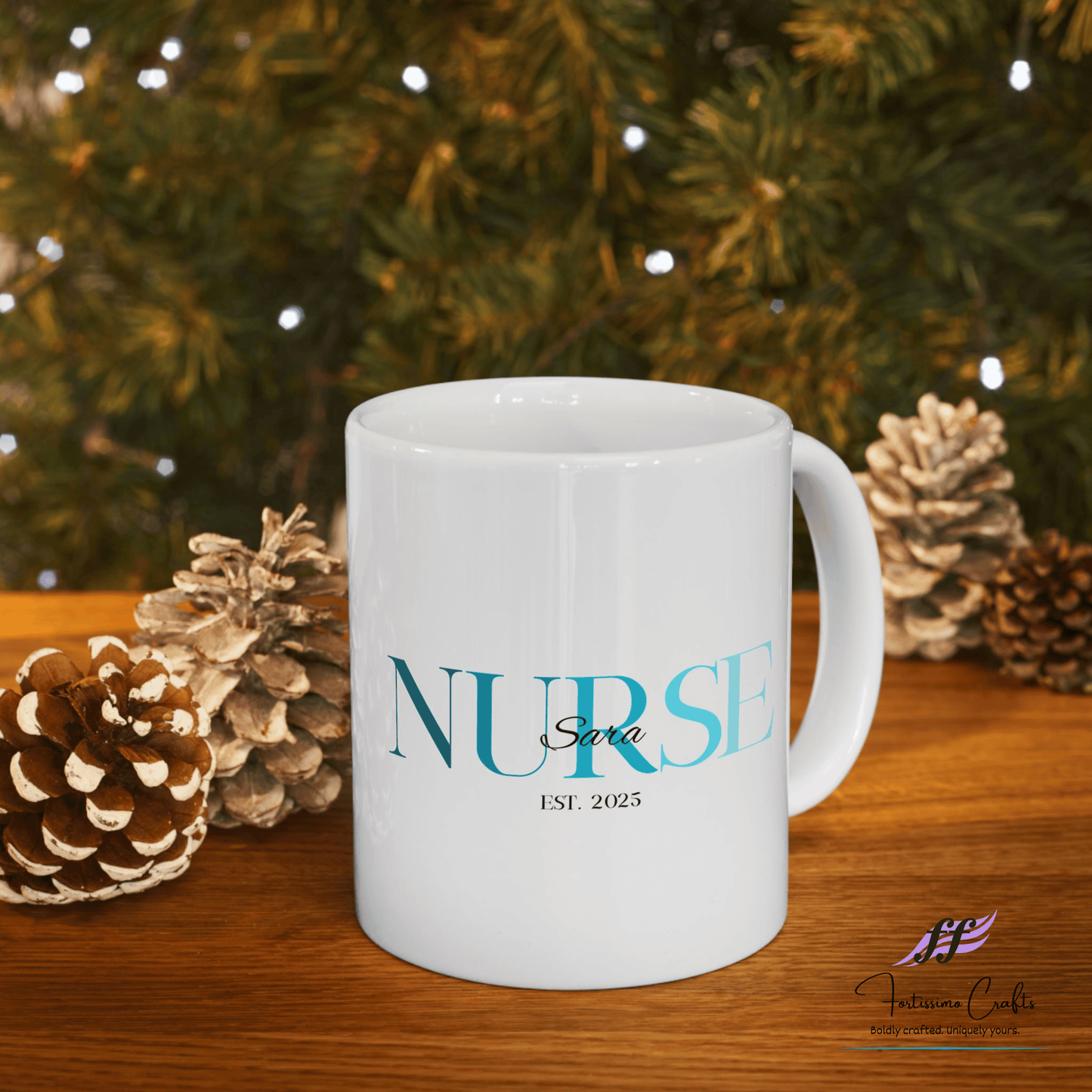 White ceramic mugs with NURSE in teal with the name Sara on top and est. 2025 underneath sitting on a table with evergreen and pinecones in the background