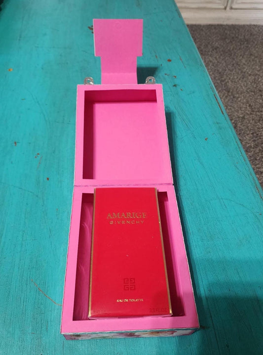 Red Givenchy perfume bottle in a pink box on a teal surface