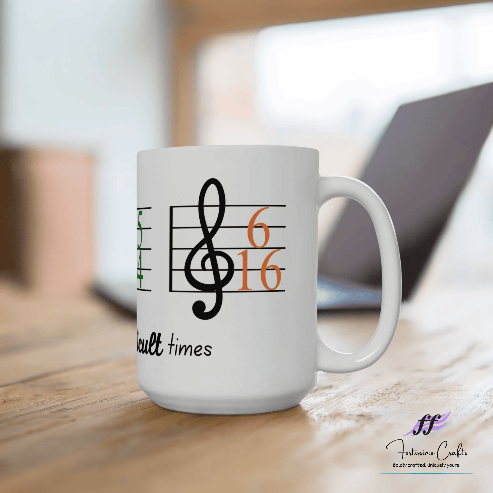 right view of 15oz white ceramic mug with music staff, 6/16 key signature and these are difficult times on a desk with laptop in the background