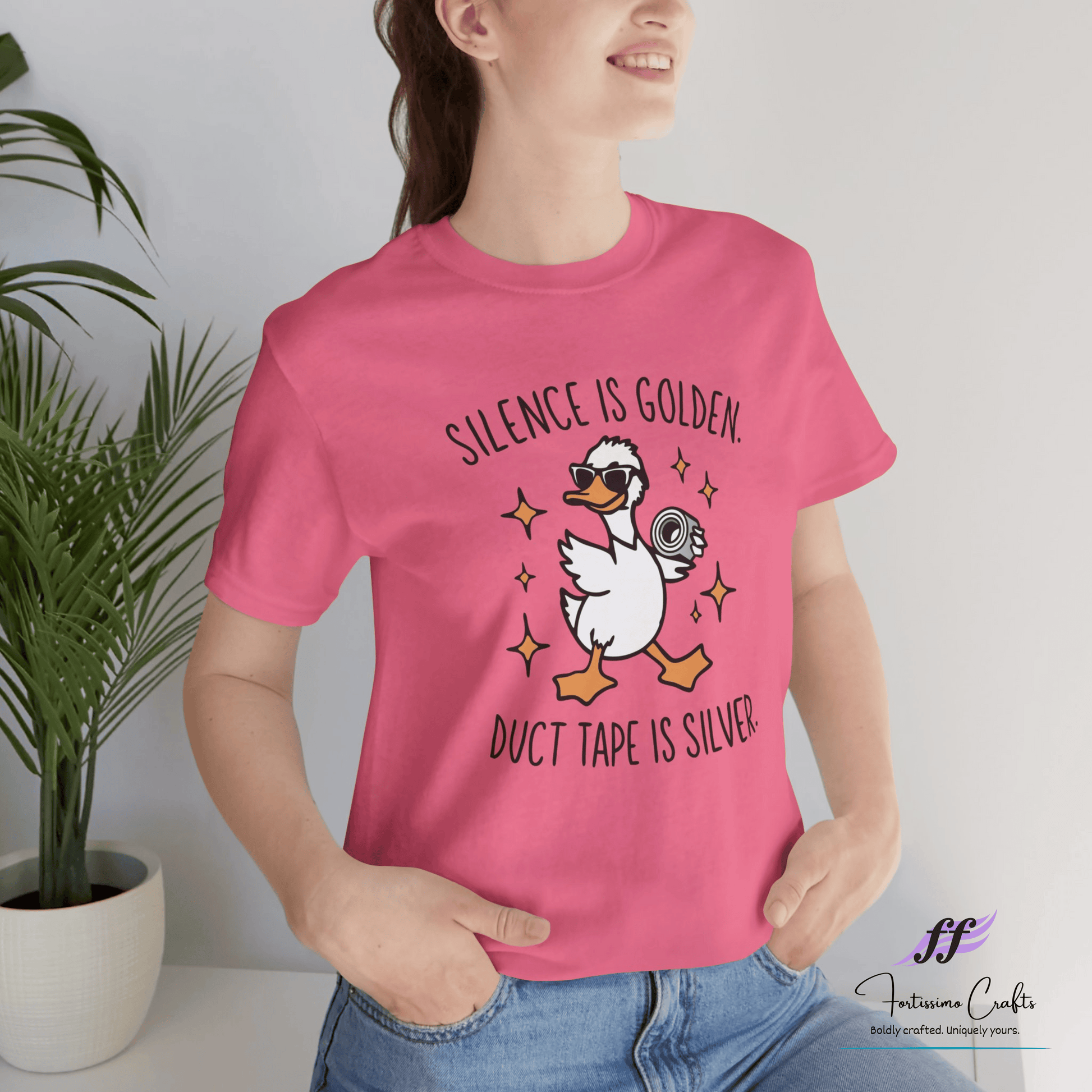 Person wearing a pink t-shirt with a graphic and text, standing against a light background.