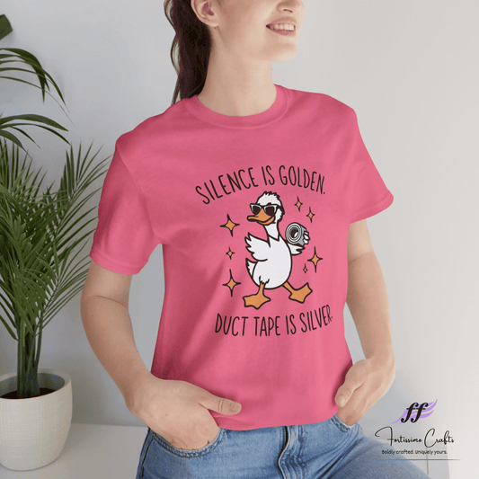 Person wearing a pink t-shirt with a graphic and text, standing against a light background.