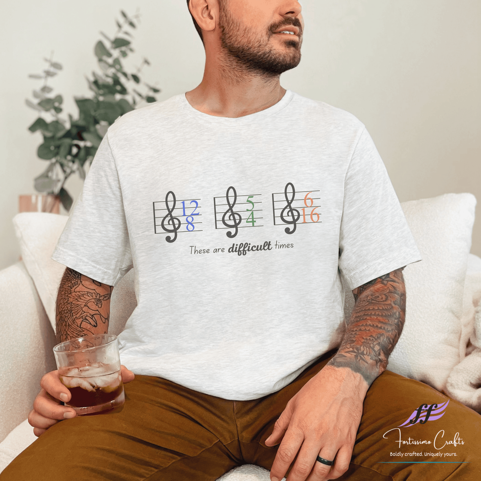 Man wearing a white t-shirt with musical note design and text, sitting on a couch.