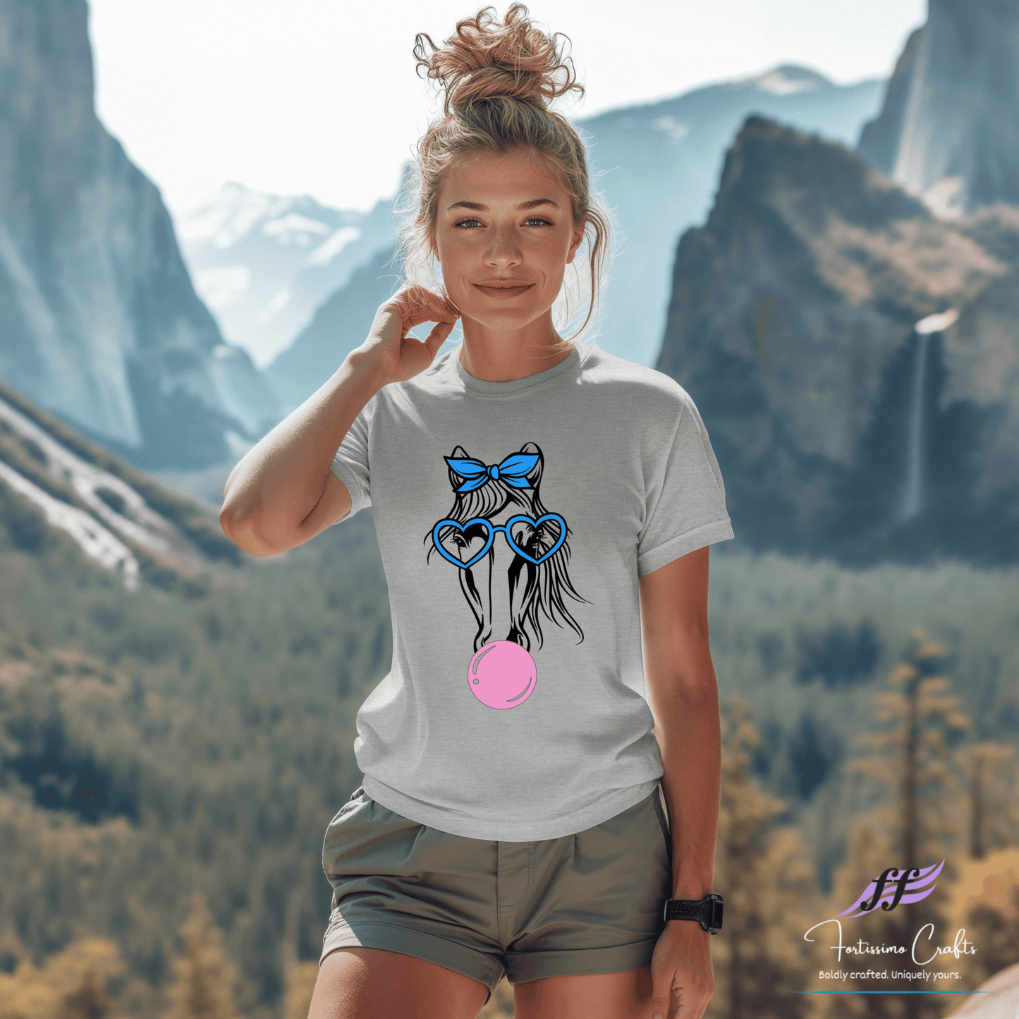 Woman wearing a t-shirt with a graphic design of a horse wearing glasses and a bow, standing in front of mountains.