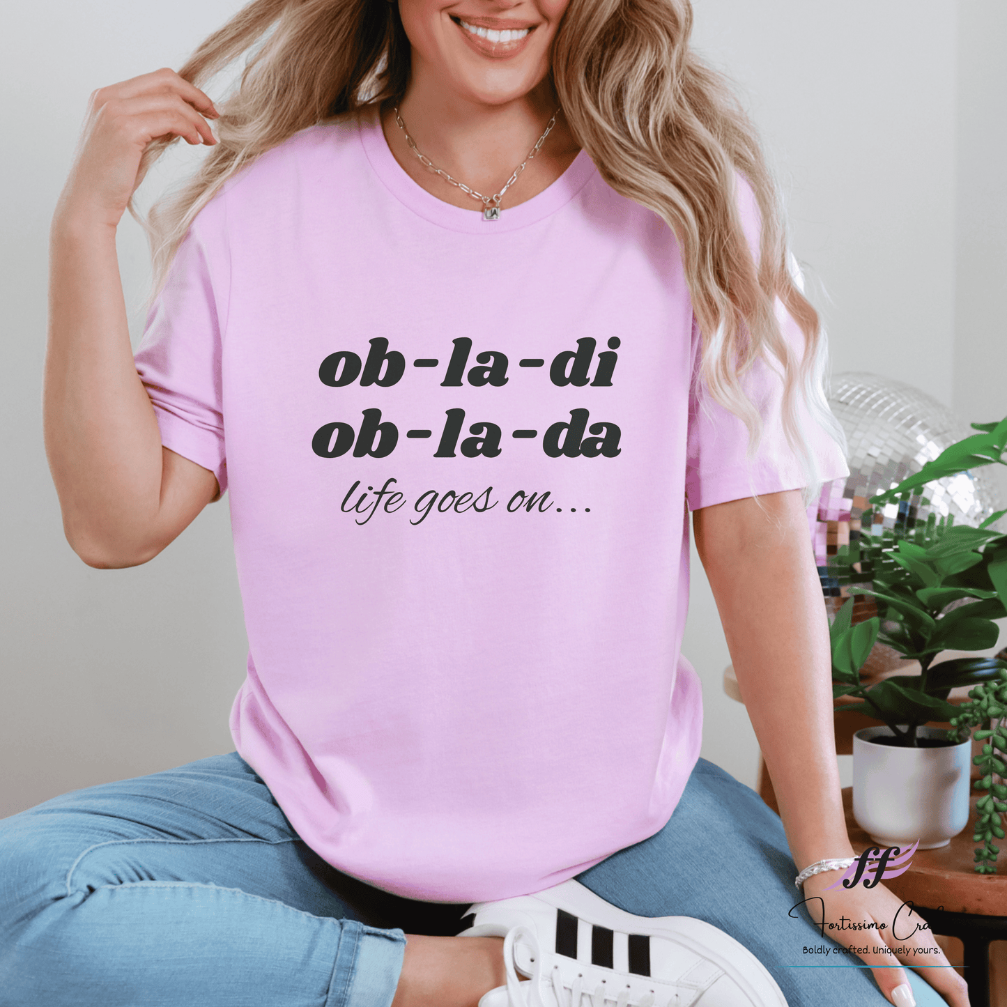 Person wearing a pink t-shirt with text, sitting indoors.