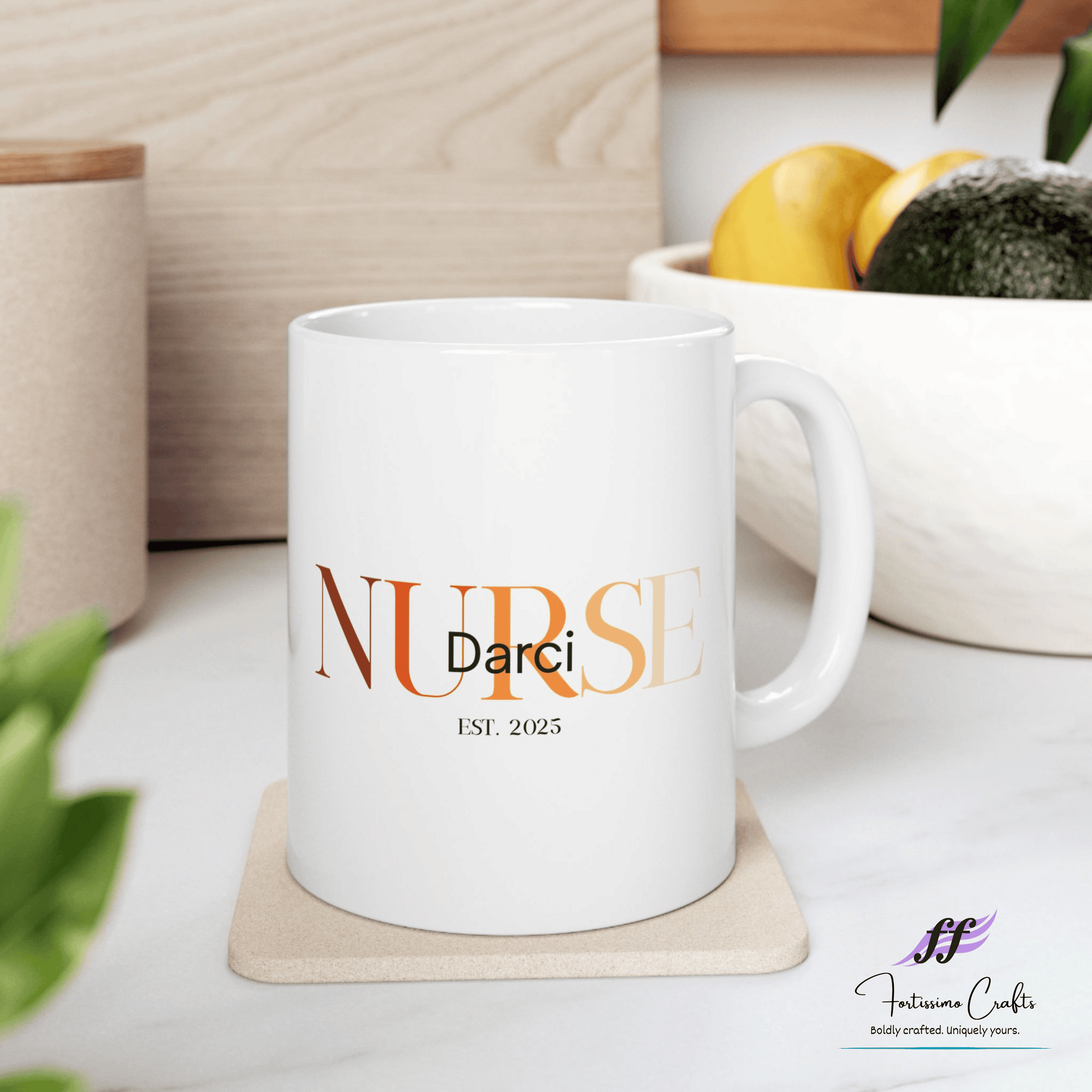 White ceramic mugs with NURSE in orange with the name Darci on top and est. 2025 underneath sitting on a table with a bowl of fruit in the background
